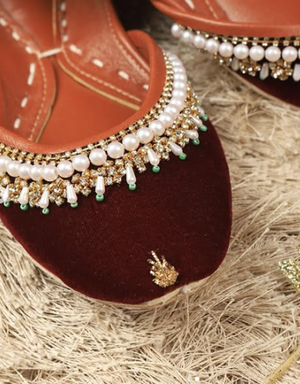 Close-up of maroon velvet-look jutti with gold-tone accents