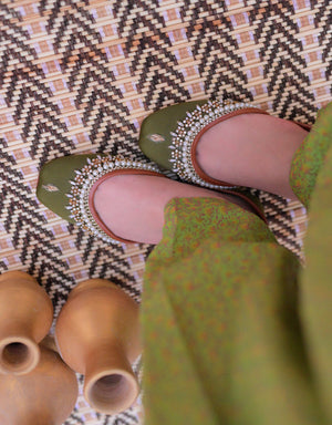 Close-up of olive green jutti with gold-tone detailing